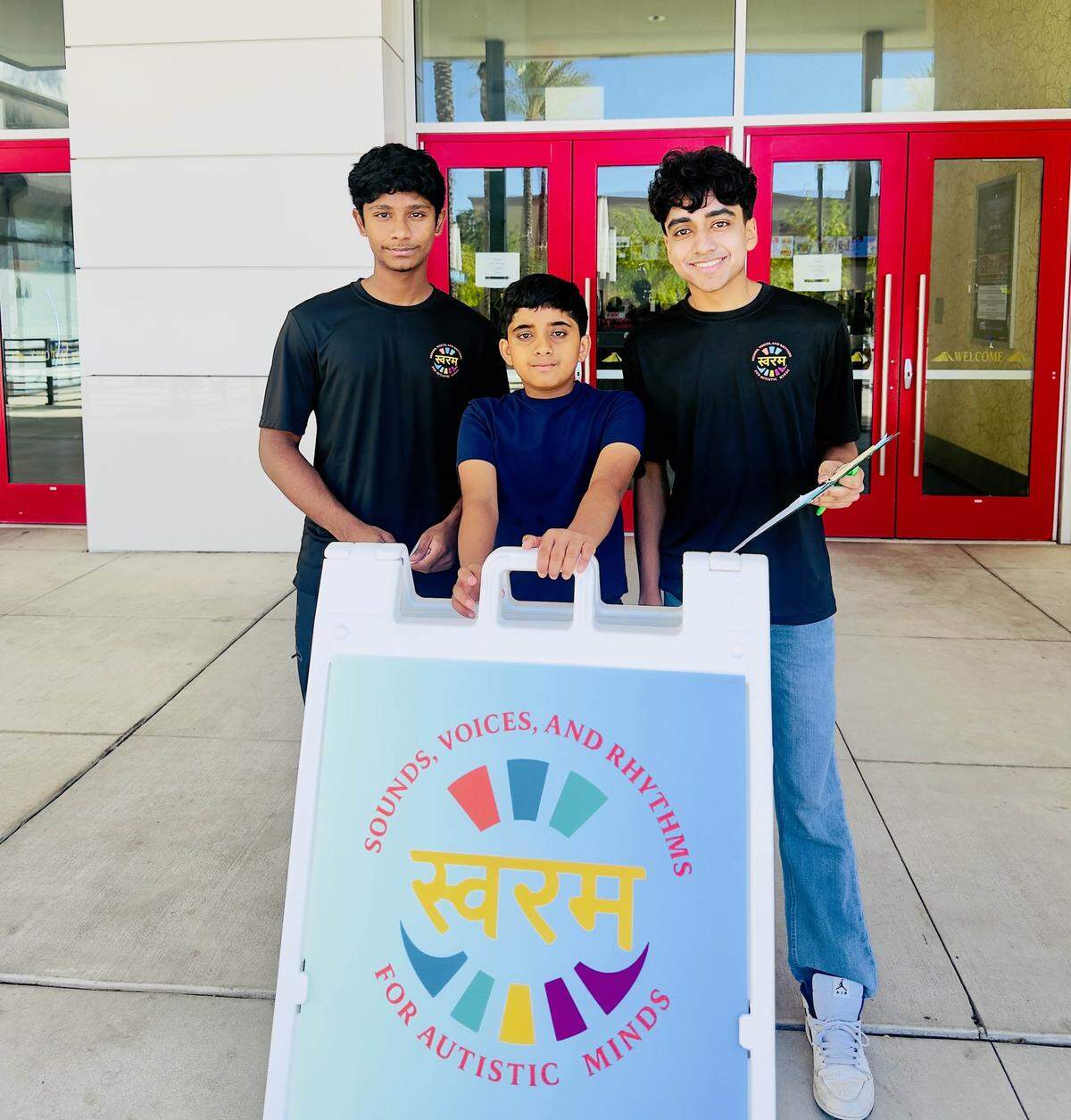 Achuth Vinay (left), a Sounds, Voices and Rhythms for Autistic Minds (SVARAM) board member, Jacob Paul (middle), an audience member and event participant, and Matthew Paul (right), SVARAM founder, pose in front of Maya Cinemas in Fresno.