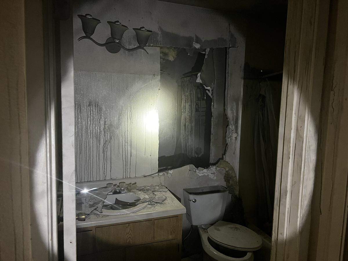 The wall of an apartment bathroom is gutted, as firefighters broke in to rescue a man and his son after the man barricaded themselves inside and set the building on fire.
