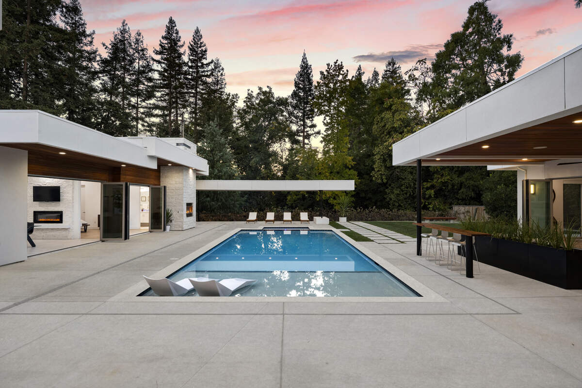 The home’s glass-lined great room opens to the resort-style pool, blurring the line between indoor living and the backyard entertaining areas.