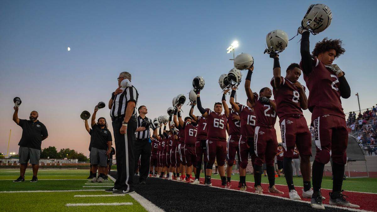 The new lights at Hiram Johnson’s football stadium shine on James Hunter (2) and his teammates as they raise their helmets at the end of the national anthem before their season opener Friday. It was the first game in the school’s newly renovated facility.