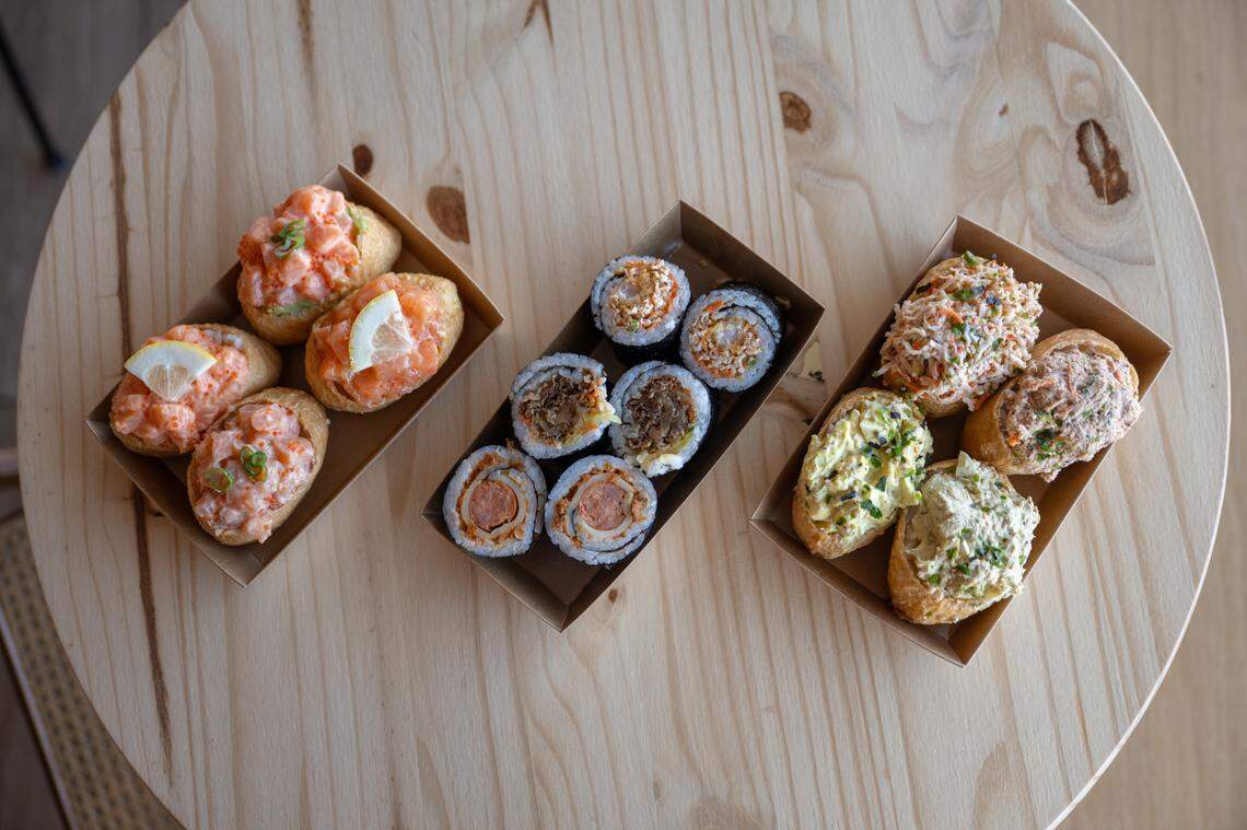 A table at Rice Theory holds trays of salmon inari ($4.95 each), a selection of rolls, and a tray of inari featuring spicy crab salad, egg salad, spicy tuna salad and tuna egg salad last week. 