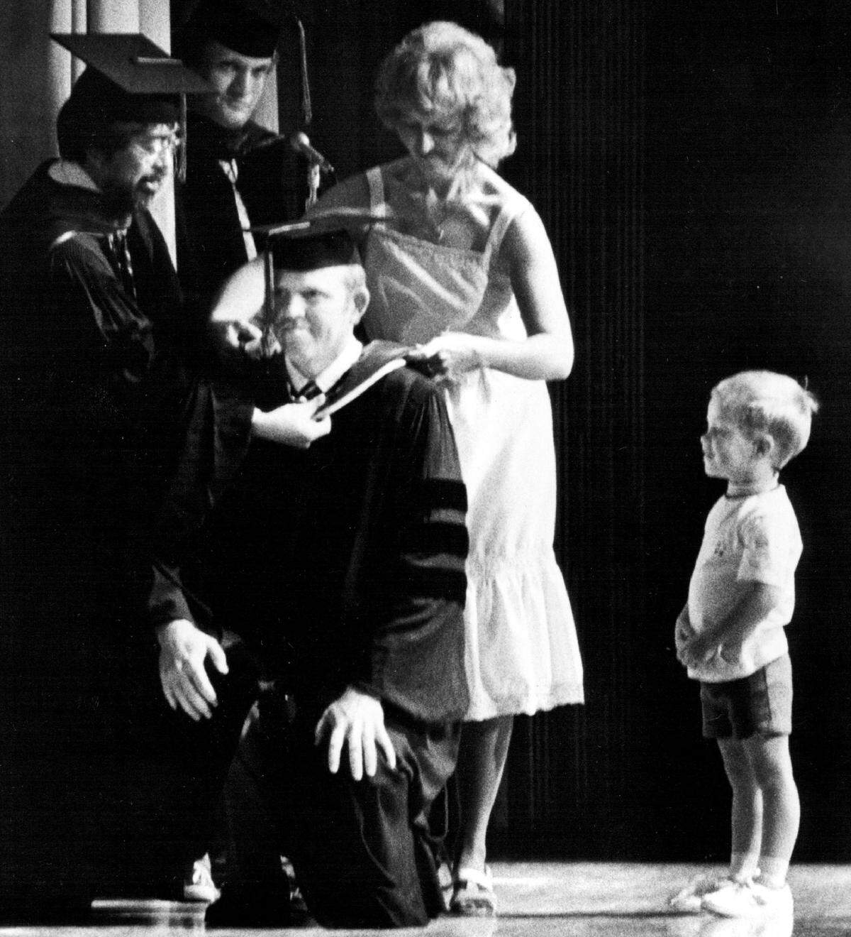 Allan Bakke receives his hood from his wife Judy during graduation ceremonies at UC Davis in 1982. Their son watches at right.