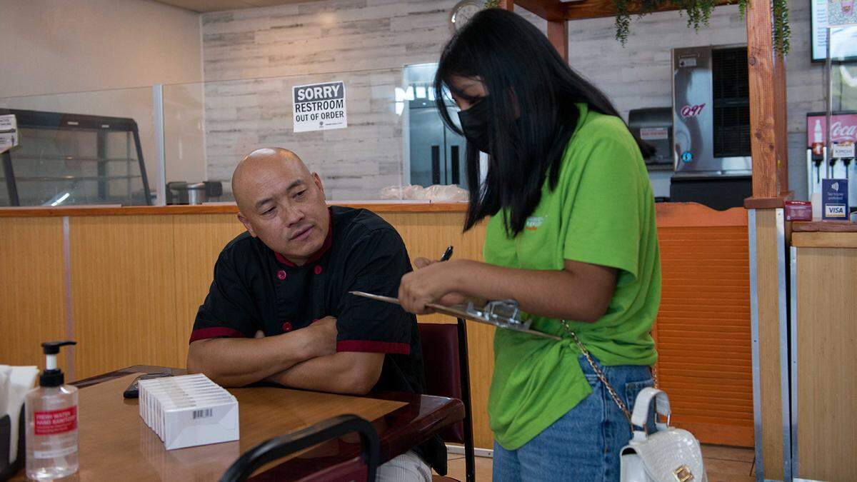 Teens deliver COVID-19 tests and information flyers to Chris Vang, left, owner of Tiger Bite Bowls, an Asian fusion restaurant in Fresno. The teens have been trained as health educators to promote COVID-19 vaccinations.