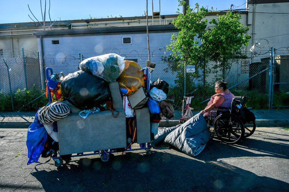 Theresa Rivera, 45, who is homeless and has an infection in her leg that prevents her from walking, tugs on a sleeping bag while packing her belongs onto a cart after receiving a citation forcing her to move from N. 14th St. in Sacramento’s River District on March 13, 2024. Homeless for 10 years, she said she didn’t understand why the police were sweeping the homeless away from resources they need at Loaves & Fishes.