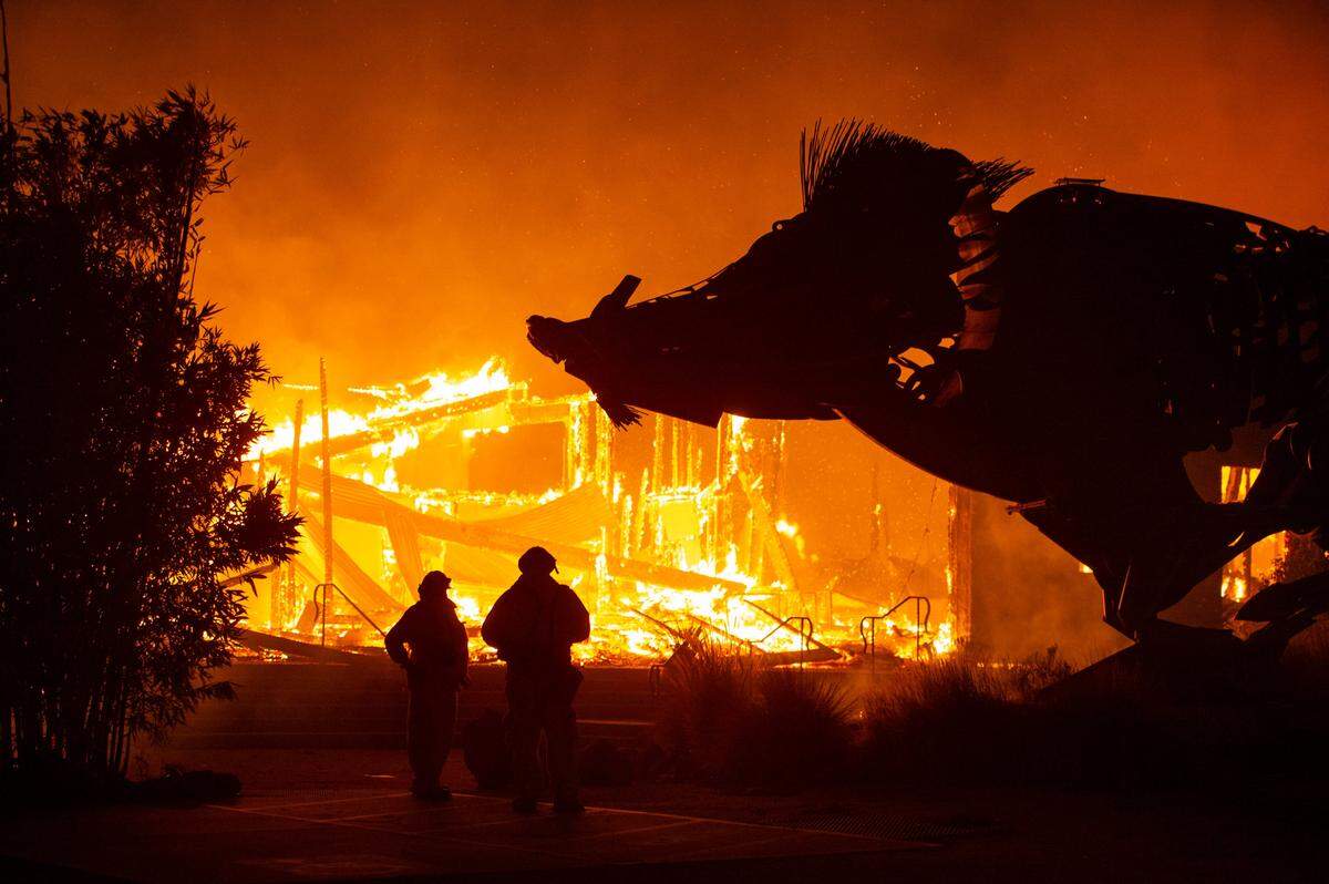 A huge sculpture of a boar looms over two firefighters as the Soda Rock Winery is consumed by the Kincade Fire early Sunday morning, Oct. 27, 2019, near the Sonoma County town of Healdsburg.