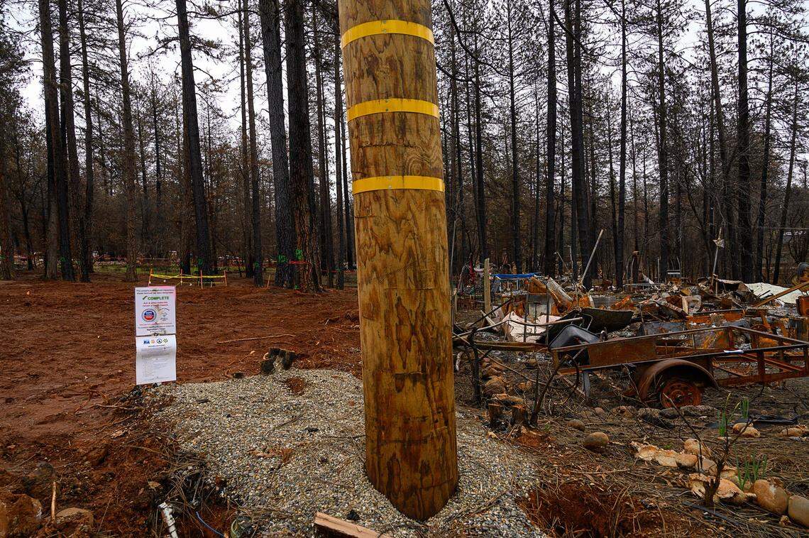A sign indicates that the property on the left has been cleared of fire debris on Tuesday in Paradise. The property on the right is waiting to be cleared.