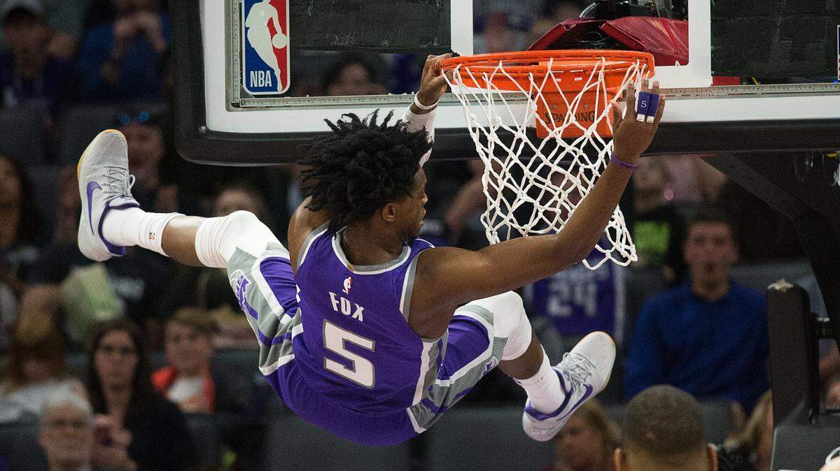 Sacramento Kings guard De’Aaron Fox (5) hangs on the basket after scoring against the Boston Celtics during a game at Golden 1 Center on Sunday March 25, 2018 in Sacramento, Calif.