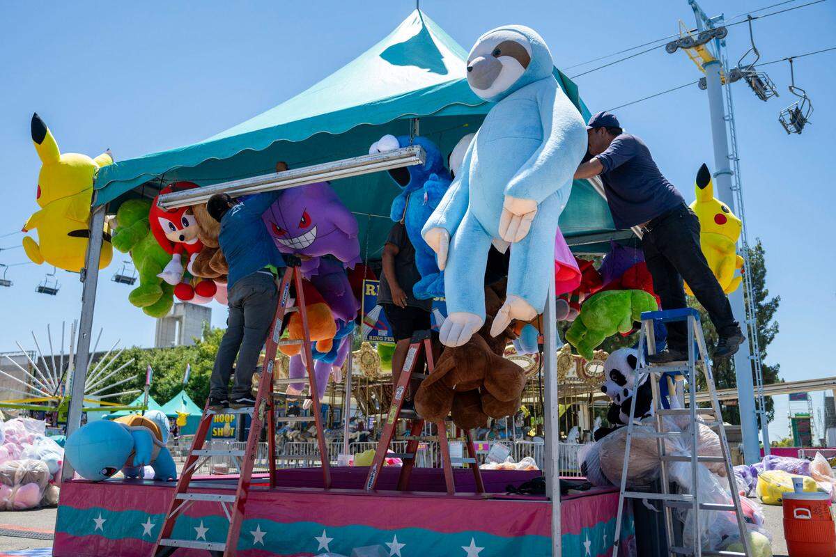Workers prepare a game booth for the California State Fair at Cal Expo on Wednesday.