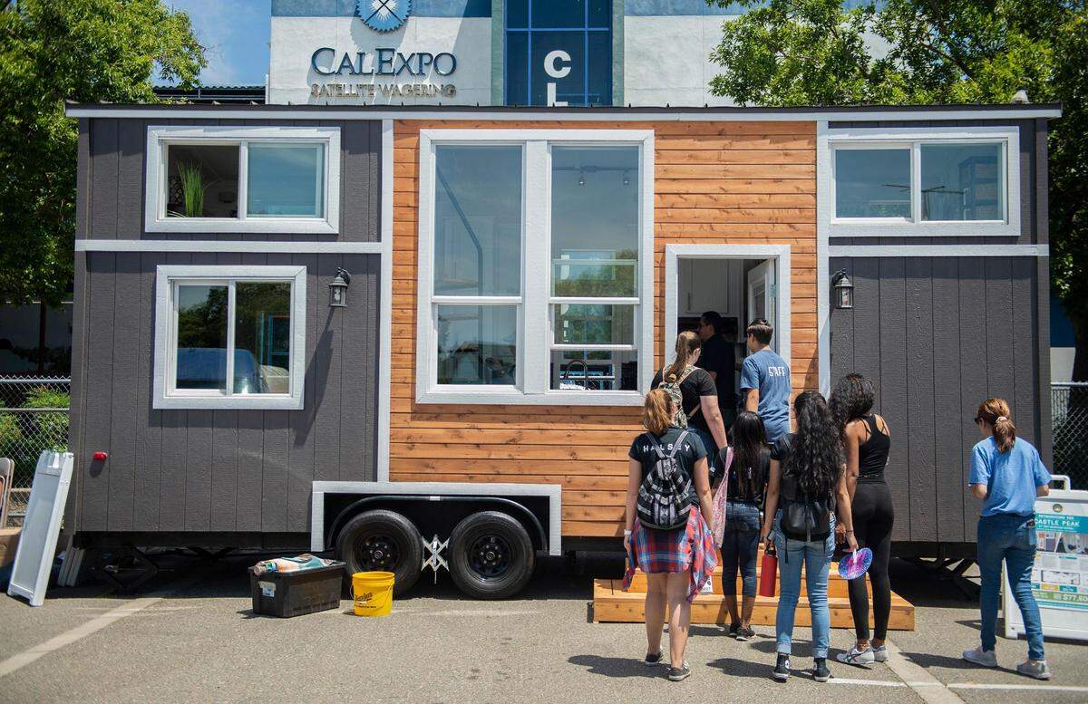 Fair goers line up to see a tiny home on wheels displayed at the California State Fair in 2018. Unconventional home builders believe their product could provide an alternative to rising California home prices.
