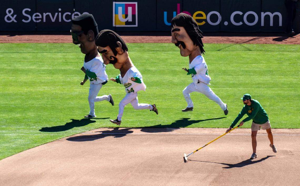 Men race around the field wearing giant masks representing former Oakland A’s players during the team’s final home game at Oakland-Alameda County Coliseum on Thursday.