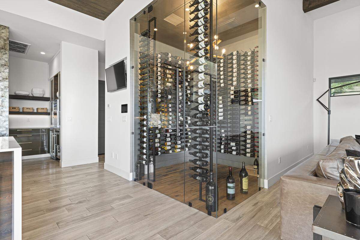A corner glass wine display, accommodating hundreds of bottles, sits in the main living area.