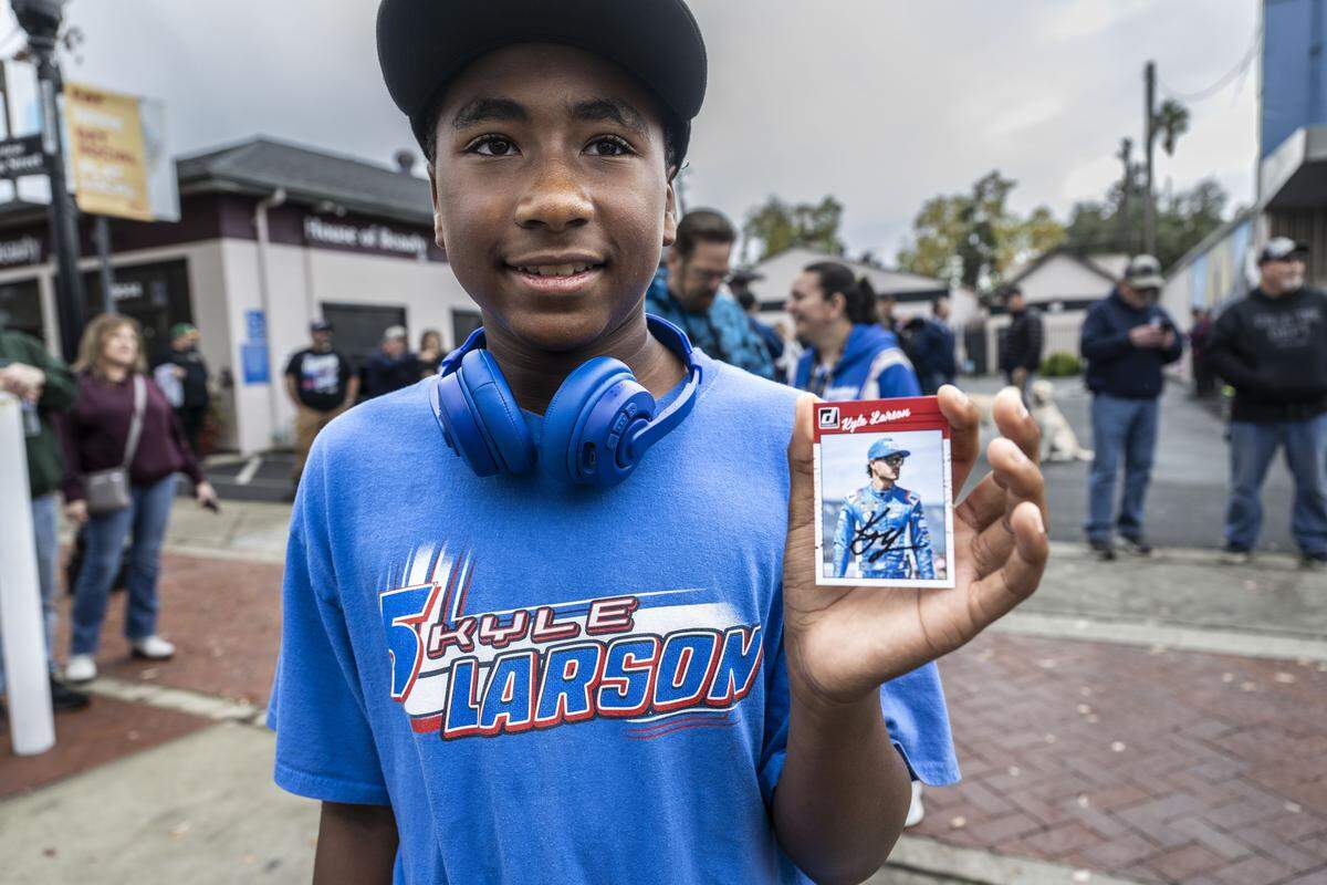 Leon Landry, 11, of Plumas Lake, holds an autographed card that Kyle Larson signed for him in Elk Grove on Friday. Larson was being honored by his hometown with a parade for winning his second NASCAR Cup Series Championship earlier this month.