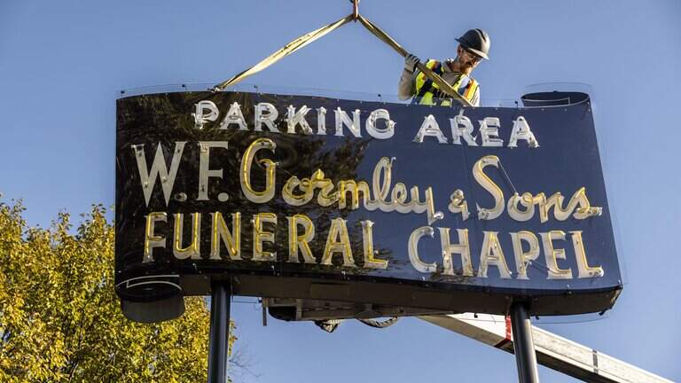 Workers install vintage W.F. Gormley & Sons neon sign at new Sacramento location