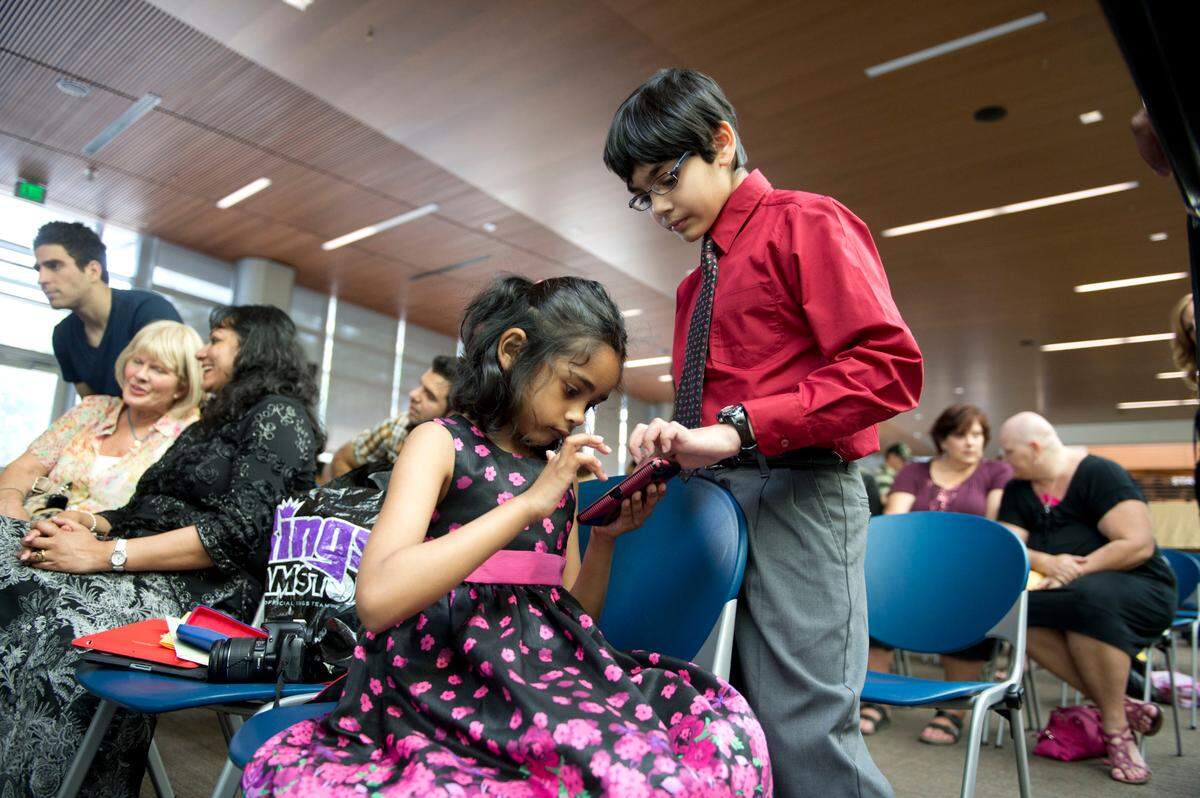 Tiara Abraham, 7, plays a game on a smart phone with her brother Tanishq Abraham, 9, who was inducted in the international honor society Phi Theta Kappa on May 3, 2013 at American River College. Tanishq is the youngest student at the school.