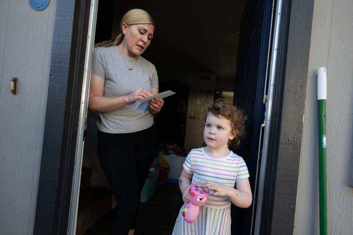Service worker Jennifer Buckley stands with daughter Nova McLean as she looks over a Measure N flyer at her doorstep in South Lake Tahoe in August.