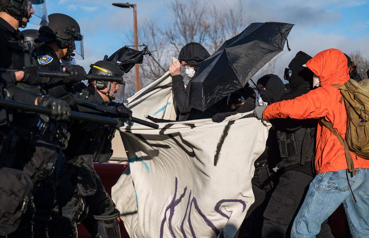University of California police encounter protesters holding a sign calling to “protect trans kids” outside the U Center before an appearance by Charlie Kirk, founder of the conservative nonprofit Turning Point USA, on Tuesday at UC Davis.
