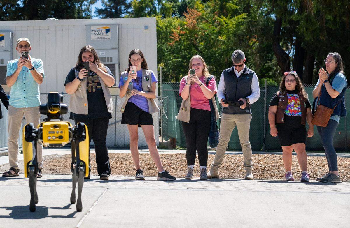 Boston Dynamics’ robot dog Spot walks in front of a group of onlookers outside the state Capitol on Thursday, Aug. 15, 2024. “It doesn’t do a lot of sort of autonomous reactions to the environment,” sales manager William Pryor, third from right, said.