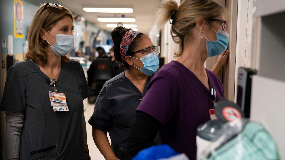 Registered Nurse Kristina Shannon, from left, chaplain Andrea Cammarota, and Emergency Room charge nurse Cathy Carter watch as medical workers try to resuscitate a patient who tested positive for coronavirus in the emergency room at Providence Holy Cross Medical Center in the Mission Hills section of Los Angeles, Thursday, Nov. 19, 2020. “I think ER nurses are a special breed,” said Shannon. “At that moment, you are just doing your job. You try not to think of the fact that that’s somebody’s mother, grandmother, or wife laying in there.” (AP Photo/Jae C. Hong)