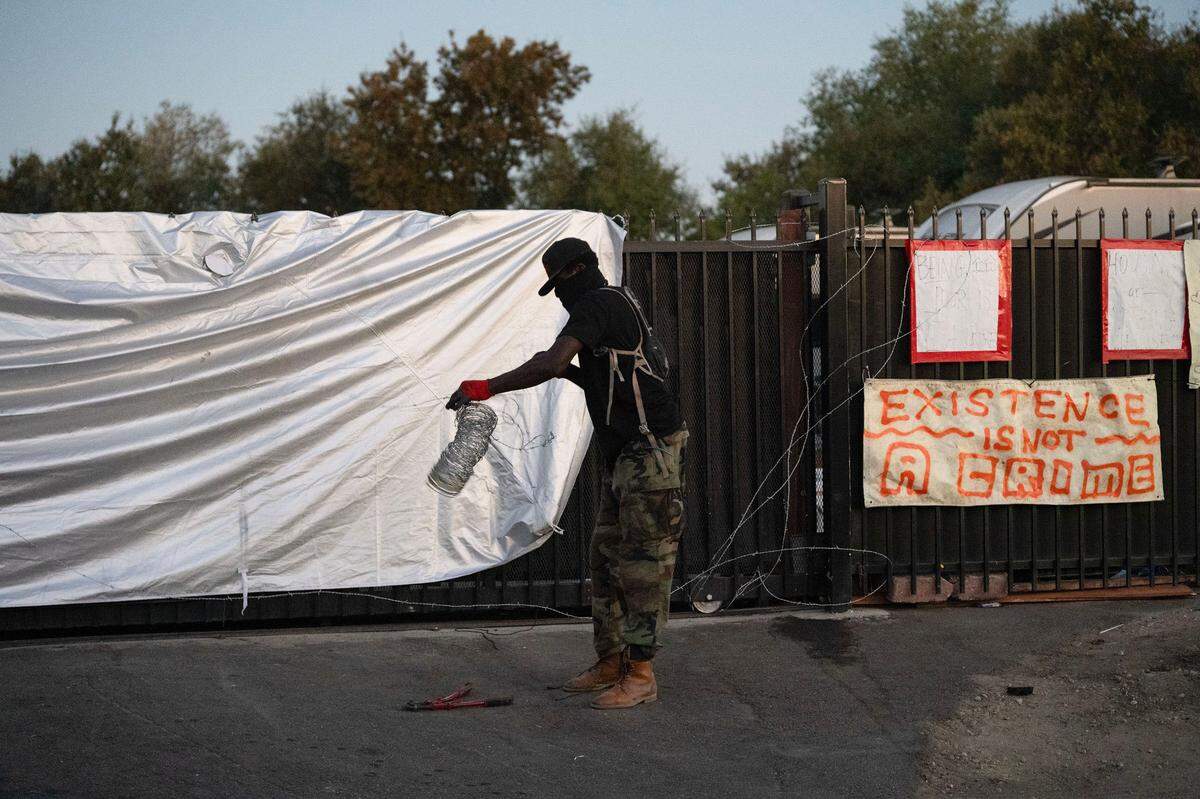 A Camp Resolution resident uses barbed wire to secure the encampments gate before the arrival of city of Sacramento crews to remove the homeless encampment on Monday, Aug. 26, 2024.