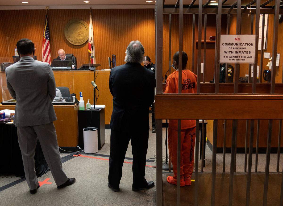 Public defenders John Buchholz and Norm Dawson stand in Sacramento Superior Court next to an arraignment cell holding suspect Mikilo Rawls during a February hearing on the murder of Emma Roark, who was found dead in the American River Parkway.