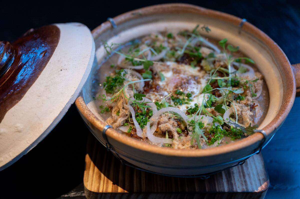 Mushroom congee is served in a clay pot with a slow-poached egg, pork floss, ginger-scallion oil, XO sauce and a fried savory Chinese donut at Chu Mai.