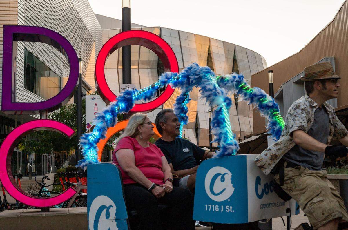 A bicycle-cab driver pedals past the DoCo sign near Golden 1 Center on his way to Sauced BBQ and Spirits last week. The arena has been dark for most of the past 16 months.
