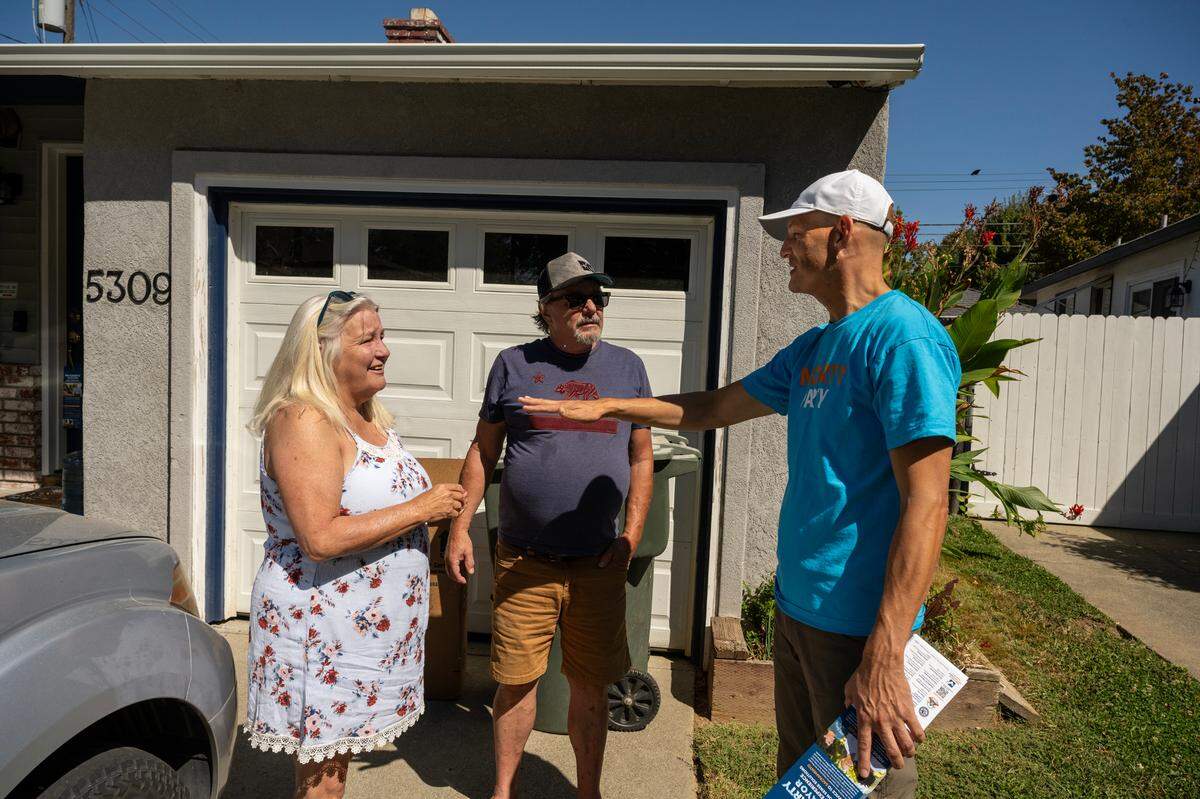 Kevin McCarty talks with Joann and Bob Chapman while canvassing in River Park on Sept. 21.