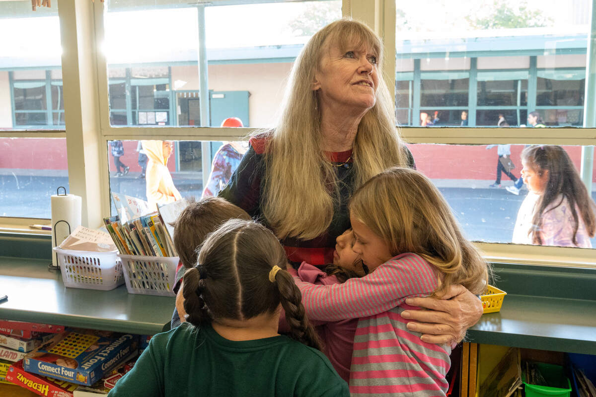 Donja Garvey, of the non-profit My Mother’s Voice, embraces children after a book and blanket give a way at Cirby Elementary School in Roseville on Friday, Nov. 18, 2022.