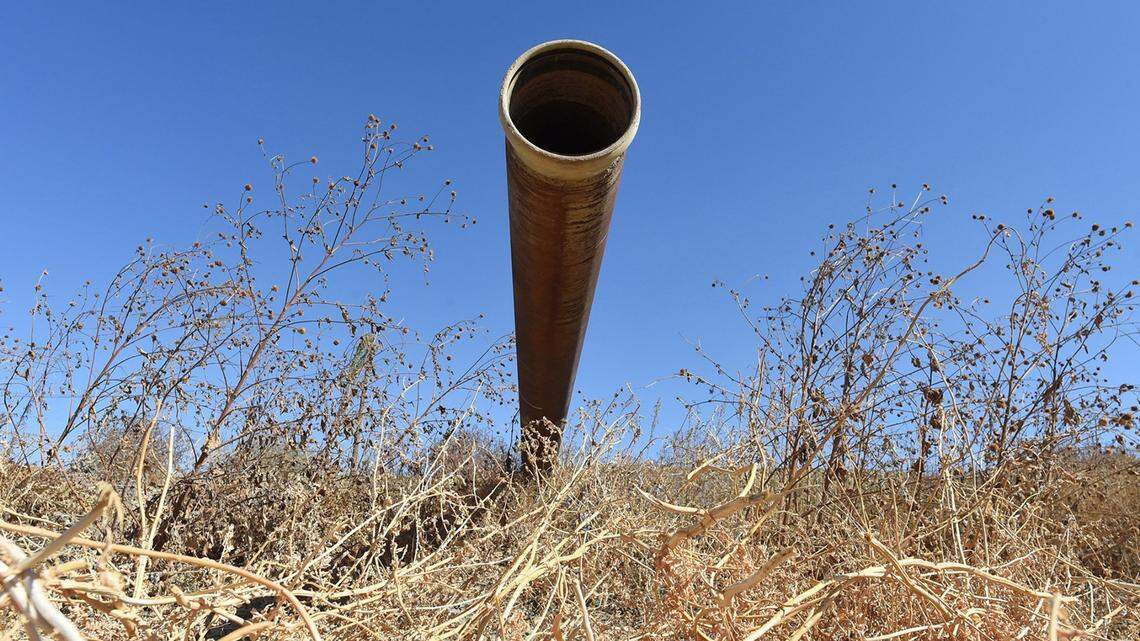 A pipe used to direct runoff water sits idle next to a fallow melon field in western Fresno County, Oct. 12, 2021.