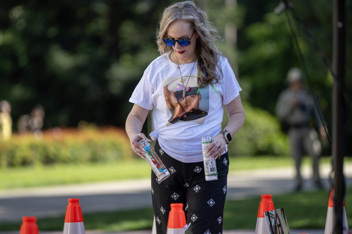 Michelle Silva places candles near cones in honor of victims of vehicular violence at a memorial rally at the California State Capitol on on Thursday, April 23, 2026. Silva wears a photograph of her husband, José Luis Silva, who was killed in a motorcycle crash in midtown Sacramento on Aug. 25, 2024.