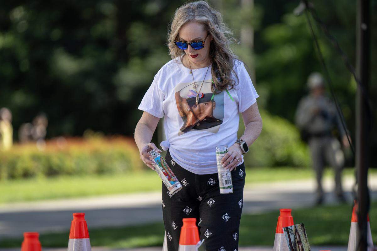 Michelle Silva places candles near cones in honor of victims of vehicular violence at a memorial rally at the state Capitol on Thursday. Silva wears a photograph of her husband, José Luis Silva, who was killed in a motorcycle crash in midtown Sacramento in 2024.
