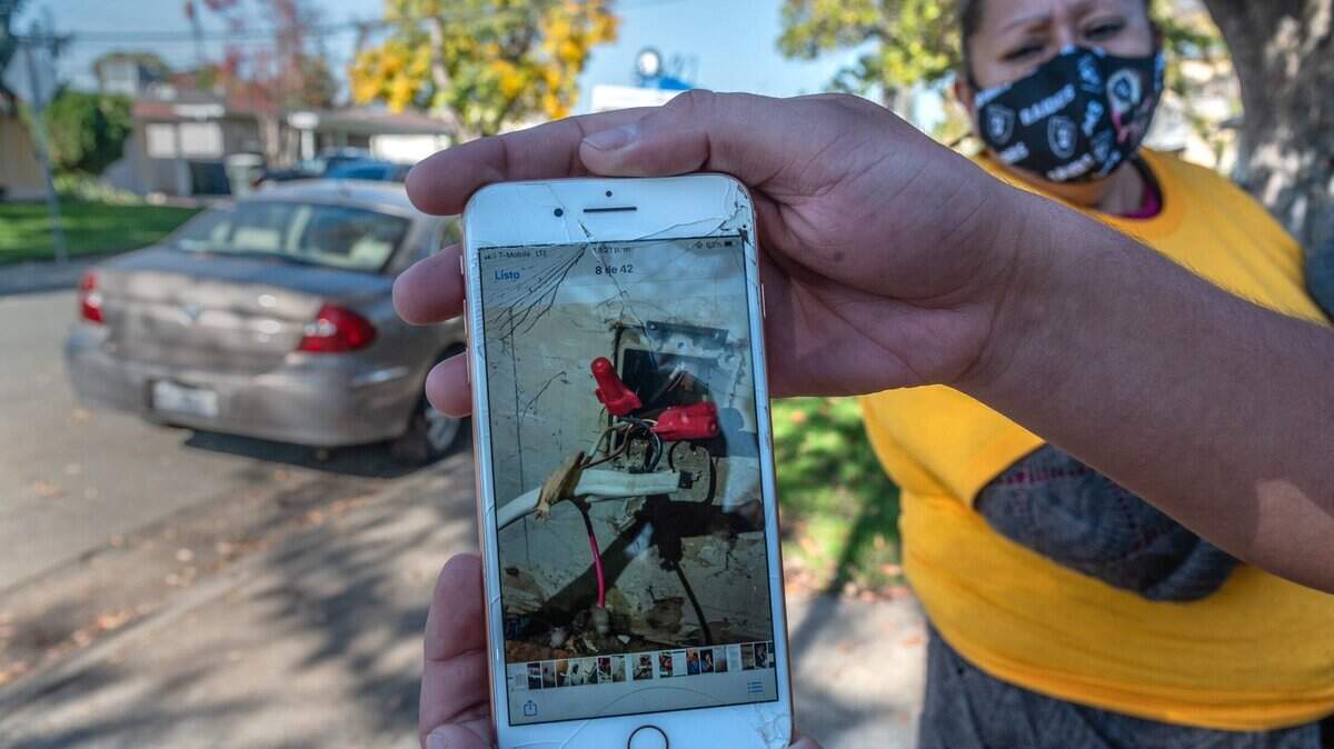 Luis Fernando Anguiano, asociado de comunicaciones de Alliance of Californians for Community Empowerment (ACCE) sostiene una foto de cables sueltos el lunes 22 de noviembre de 2021, que Eduviges García, a la derecha, dice que su casero, Garcia Reality, no reparó y llevó a que una de sus hijas se electrocutara y necesitara atención médica. García recibió un aviso de la policía informándole que la familia tiene que irse antes del miércoles.
