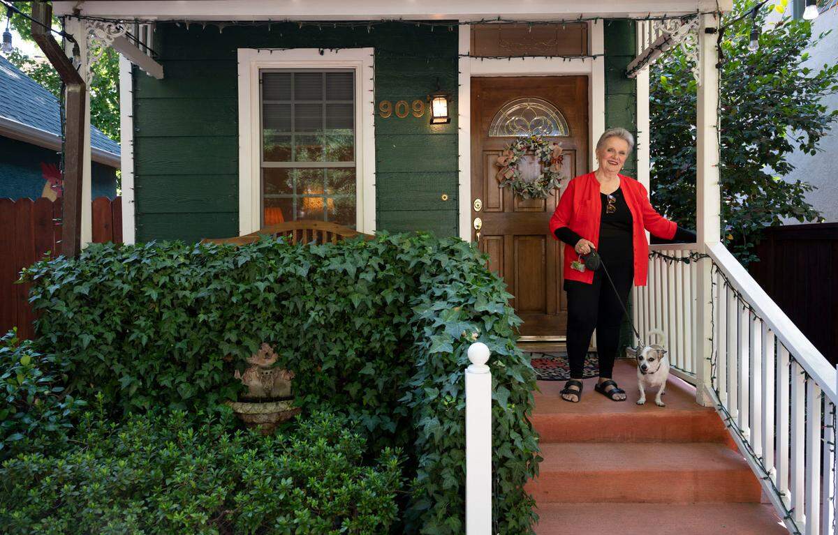 Rebekah Christensen stands on the porch “Little House,” of her 632-square-foot home with her dog Bingo in Sacramento’s Boulevard Park neighborhood Sunday, August. 25, 2024. The historic home built in the 1890’s has survived years of redevelopment.