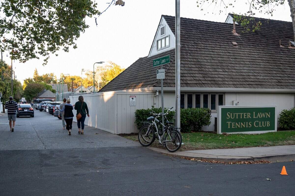 People walk down Sutter Lawn Alley to enter a private community meeting at Sutter Lawn Tennis Club in East Sacramento on Monday, Oct. 24, 2022, about the fatal shooting near the club last week.