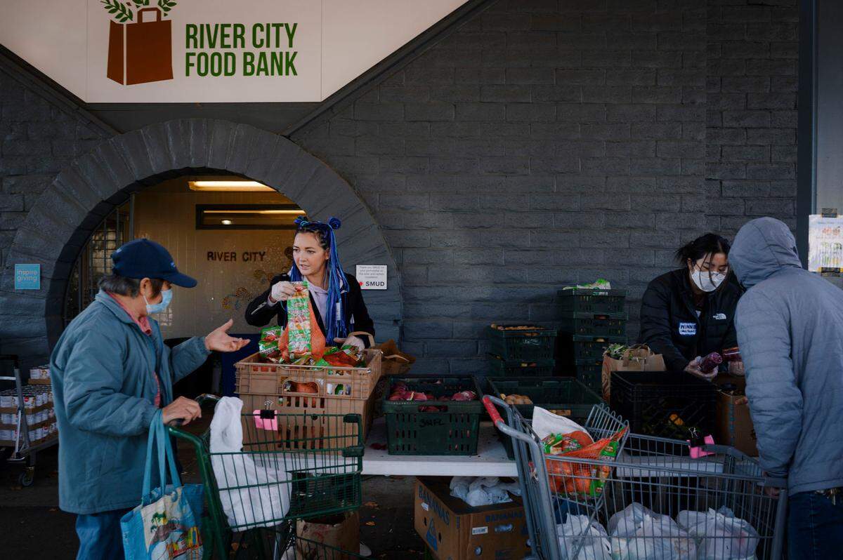 Volunteers Anna Vostrikova, left, and Winnie Liao pass out fruits and vegetables at River City Food Bank in Sacramento in December.