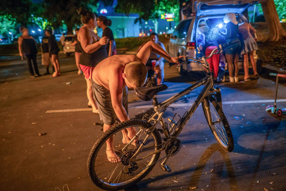 Keith-Dalton Smith, 11, checks his bicycle as his sister, Kassidy-Renée, 10, and her friends search for belongings in the back of their van, right, on Wednesday in Sacramento. Families were preparing to sleep in their vehicles after they were not allowed back into a city-funded shelter after the program changed.