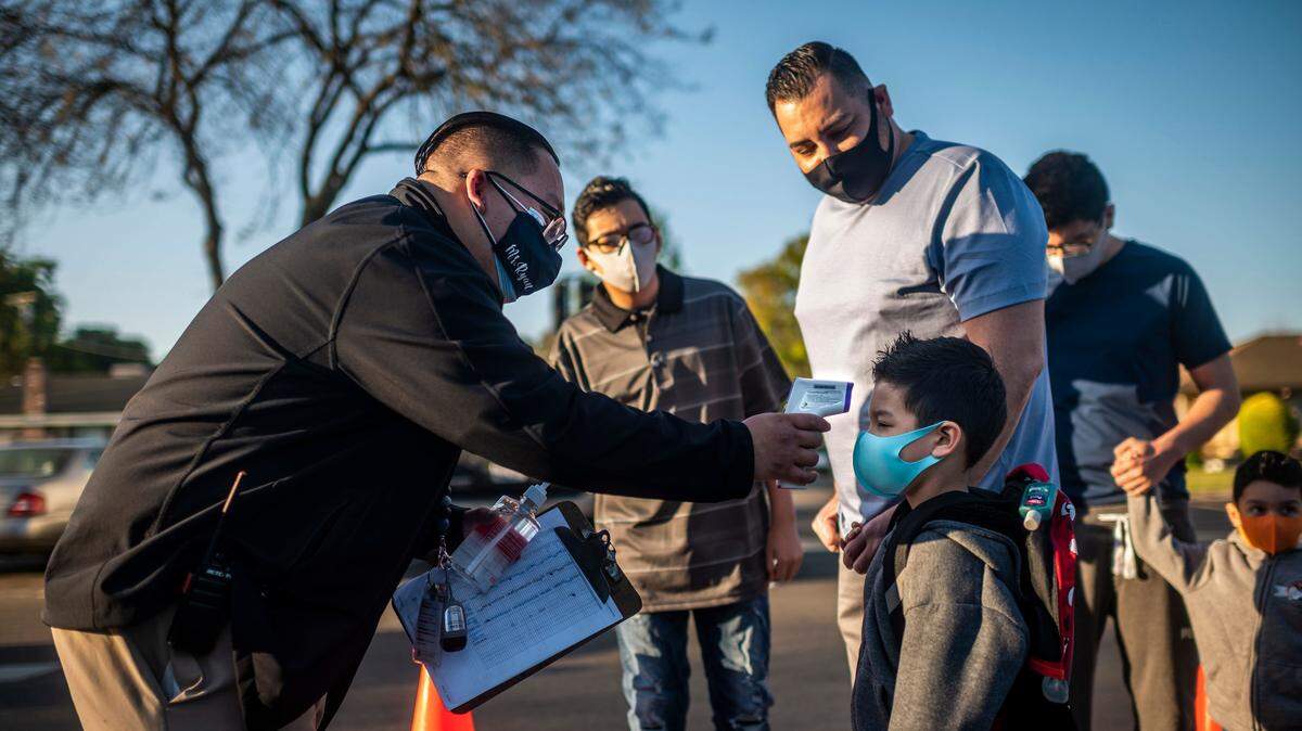 Luke Henly, 5, has his temperature checked at the front of the school before his first day back to in-person instruction at John Cabrillo Elementary in Sacramento on Thursday, April 8, 2021. Members of the SEIU 1021 union and teachers union may strike April 22.
