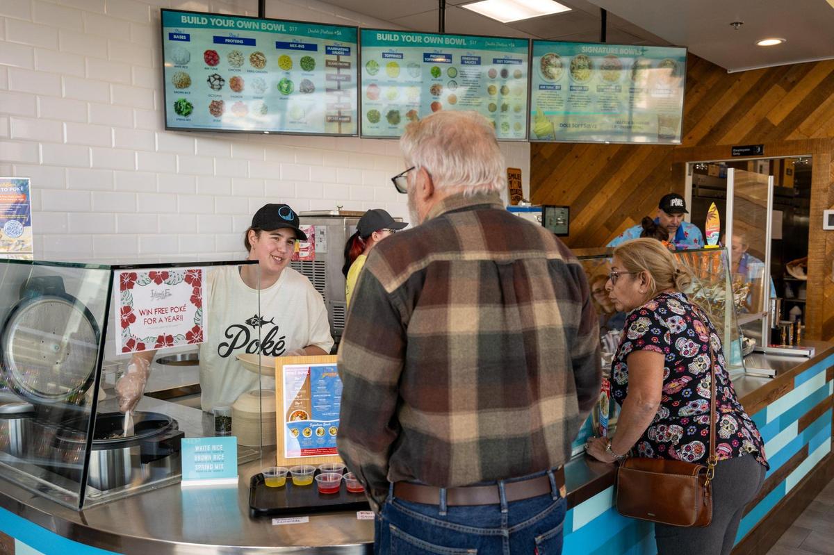 Nikki Martinez takes an order from Bob and Millie Schoreder at Island Fin Poké Co. in the Delta Shores shopping center on Monday in Sacramento. It was the Hawaiian-themed restaurant’s opening day.