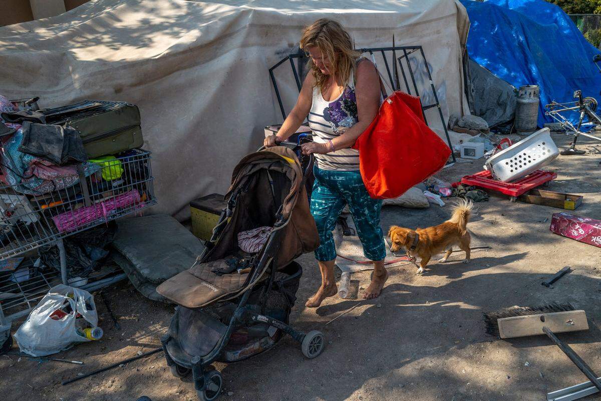 Becky Brown walks with her dog at a homeless encampment across the street from Garden Valley Elementary School in South Natomas on Friday. My family and friends know that I live here and know where to find me, said Brown who worries if she moves someplace else without a phone they will not be able to find her. Thats what really frightens me, she said.