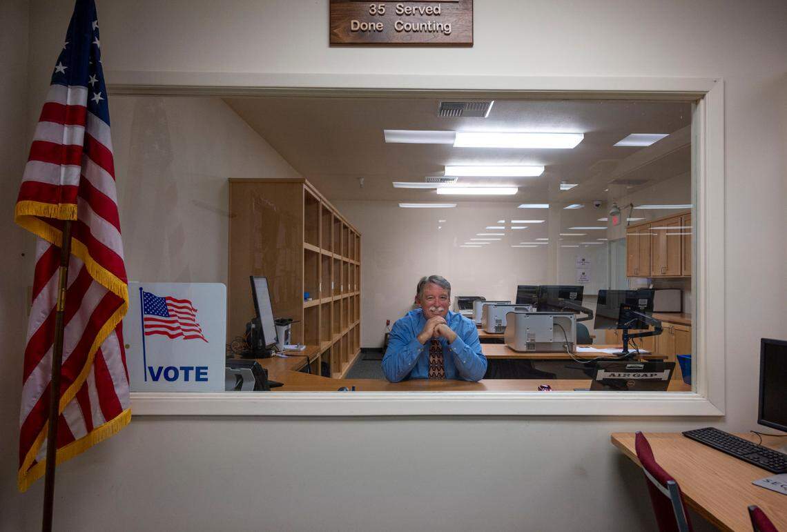 Bill O’Neill, registrar of voters for El Dorado County, sits earlier this month in the ballot tabulation room behind a big window where the public can watch ballots being counted from the elections office lobby.