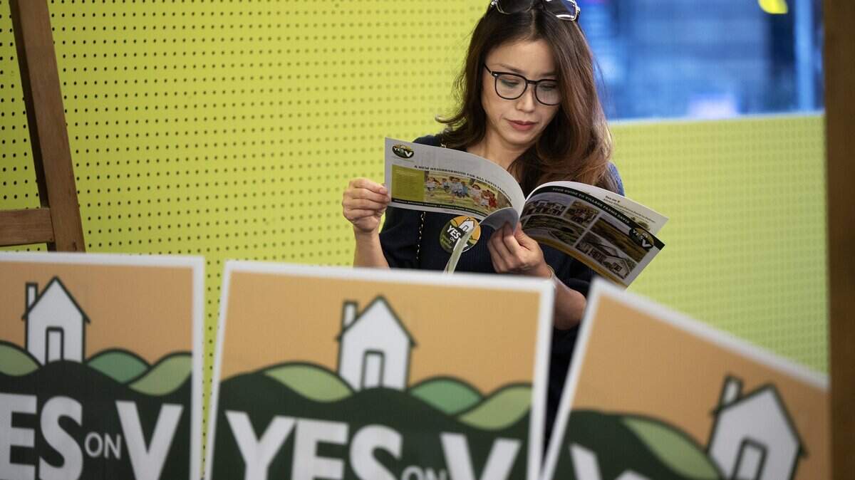 Ping Zimmerman looks through some literature at the Yes on V kick-off rally in Davis on March 4. The measure, which would allow a 498-acre development with 1,800 homes on the city's northern boundary, is trailing by a thin margin with only signature cure ballots outstanding.