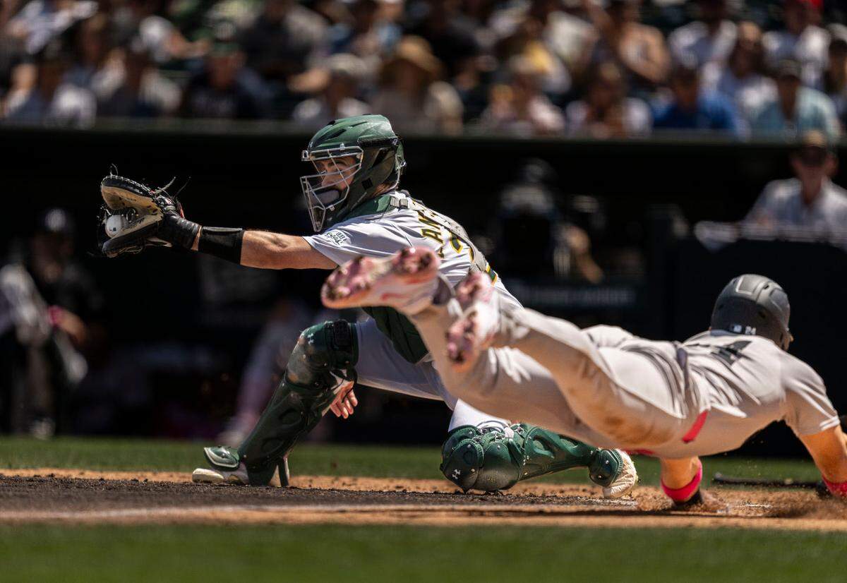 Athletics catcher Shea Langeliers (23) catches the ball as New York Yankees outfielder Jasson Domínguez (24) slides safe at home during a MLB game against at Sutter Health Park on Sunday, April 11, 2025.
