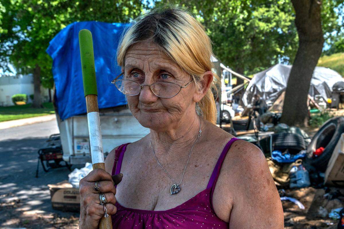 Helping clean up a mess from a burnt motor home in April 2021, Gwen Mayse, tears up as she talks about her struggle to get a home over the past five years. “Tired of living out here like this but everything is too expensive to get into,” she said. “We’ve been out here way too long.”