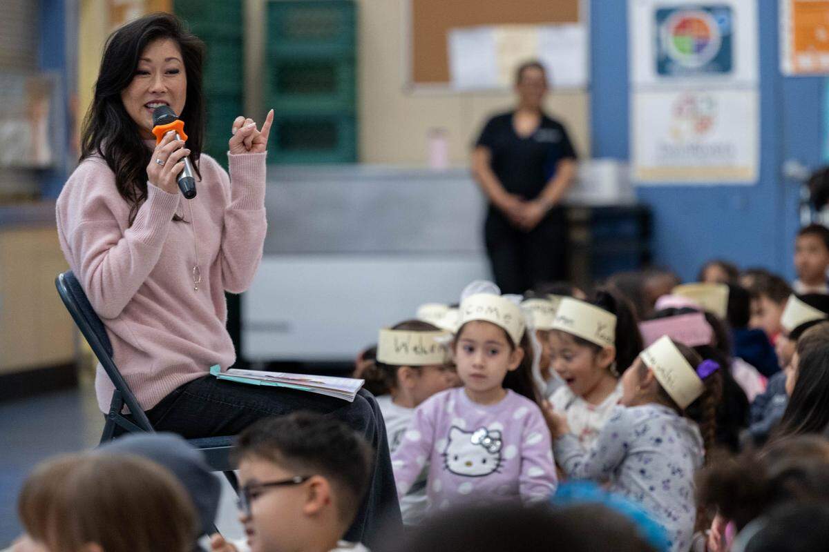 Olympic gold medalist figure skater Kristi Yamaguchi makes a pinky promise with a student to keep learning to read as she reads from her book “Cara’s Kindness” to students at Hazel Strauch Elementary School in Sacramento on Monday.