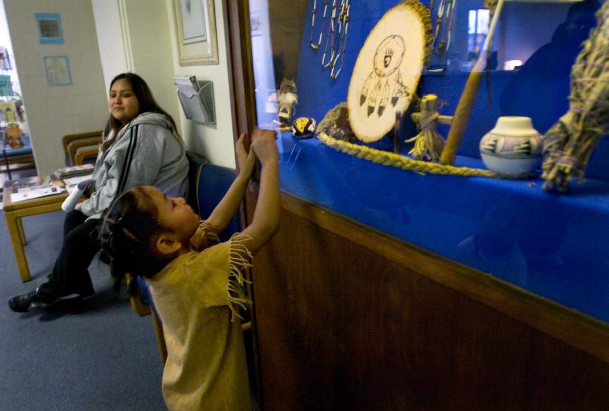 Alyssa Ringlero, 4, peers into a display case of Native American cultural items while waiting with mom, Dianna Ringlero, in a patient waiting area inside the Sacramento Native American Health Center in 2007.