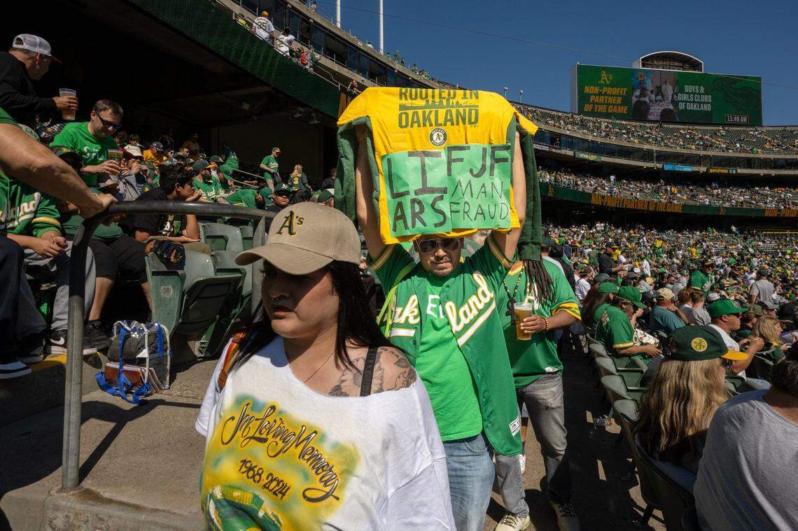 Oakland A’s fans walk the Oakland-Alameda County Coliseum aisles with signs of frustration and apparel signifying the end of an era before the team’s final game in Oakland on Thursday.