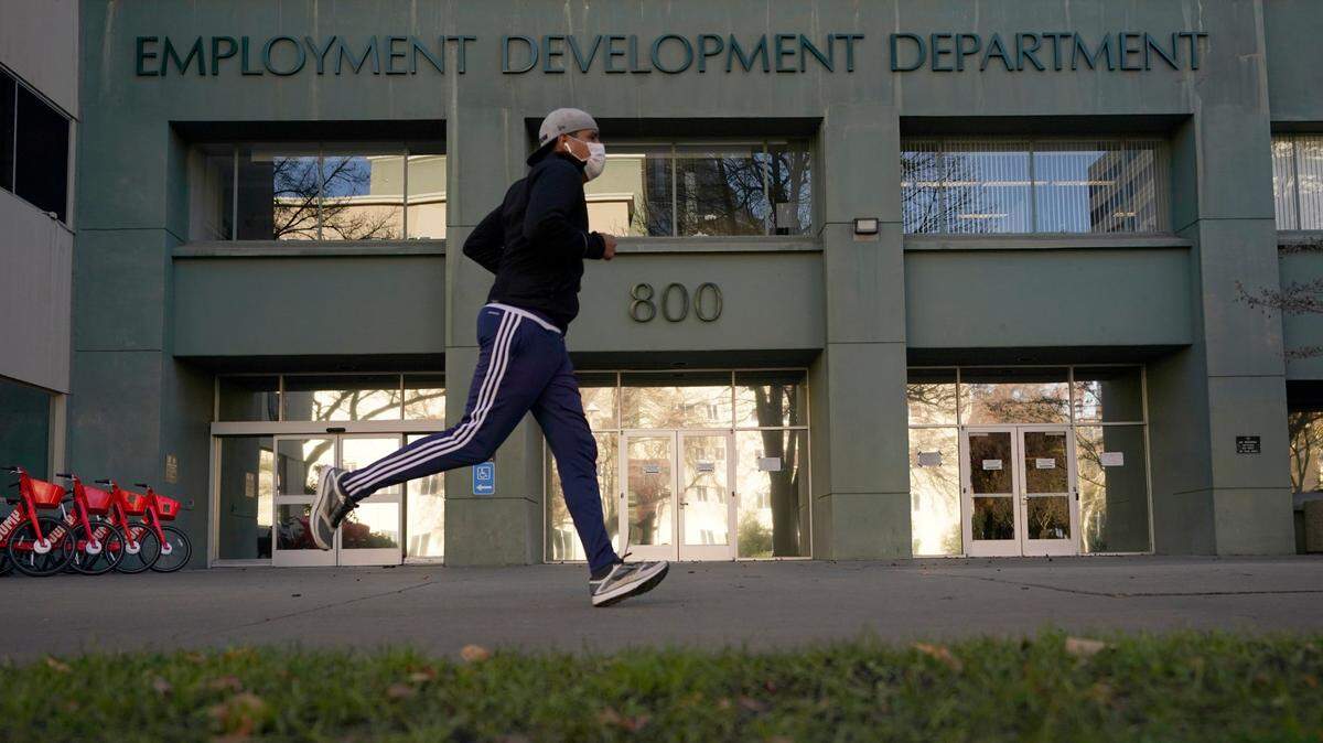 In this December 2020 file photo, a runner passes the office of the California Employment Development Department in Sacramento. As many as 100,000 Californians may still be eligible for COVID-related benefits. EDD is mailing notices to anyone who may qualify. (AP Photo/Rich Pedroncelli, File)