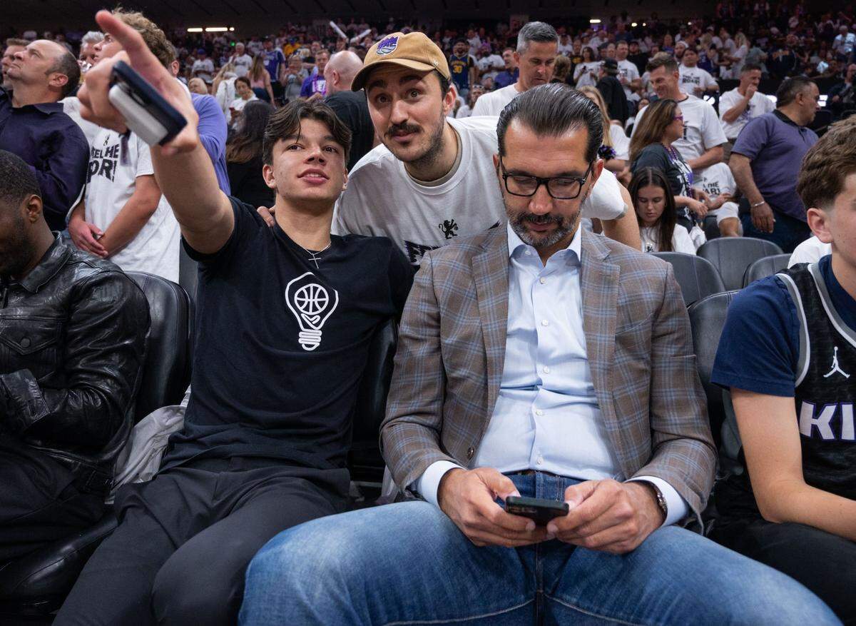 Andrej Stojakovic talks with family friend Conti Kolokotronis, as he sits with his father and former Kings player Peja Stojakovic, during Game 7 of the first-round NBA playoff series at Golden 1 Center on Sunday, April 30, 2023.