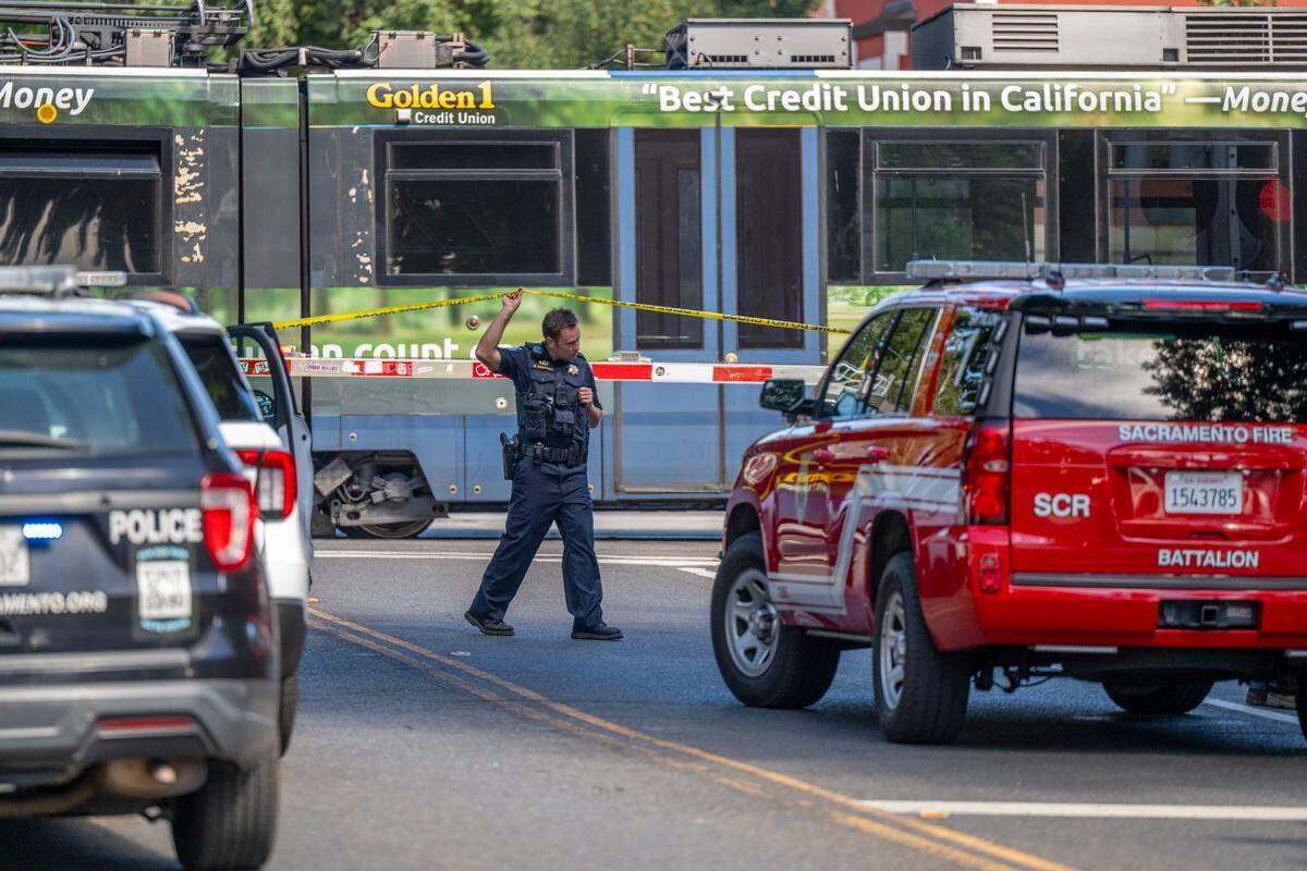 A Sacramento police officer leaves the scene where a man was struck by a light rail train while riding an electric scooter in midtown Sacramento on Monday.