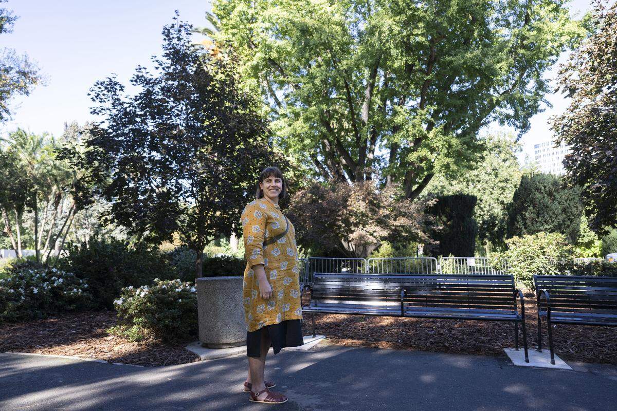 Geneva Kraus, of Sacramento, stands in front of a ginkgo tree that was fenced off to keep people from stepping on its smelly fruit on Monday. “The fruit has a distinctive fragrance. It smells kind of cheesy,” Kraus said of the odor emanating from the dropped fruit.   